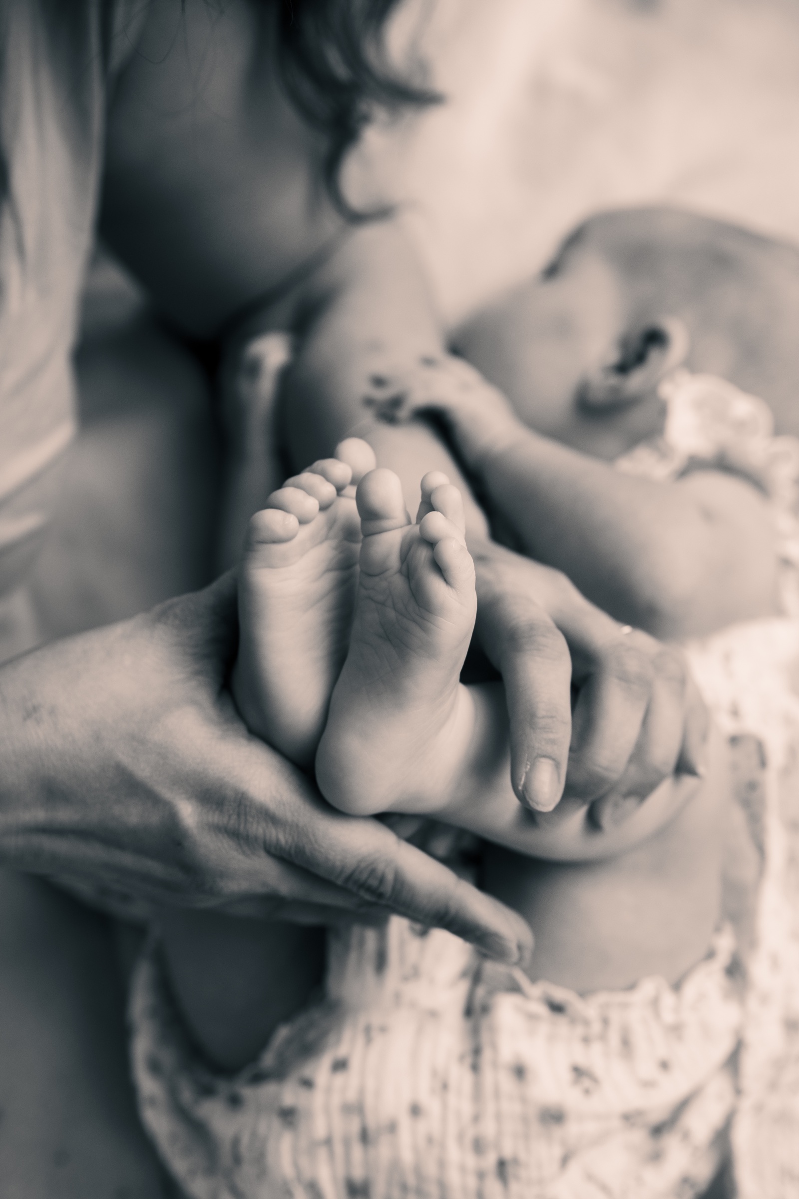 Zarte Babyfüße in den Händen der Mutter als Schwarzweißaufnahme
