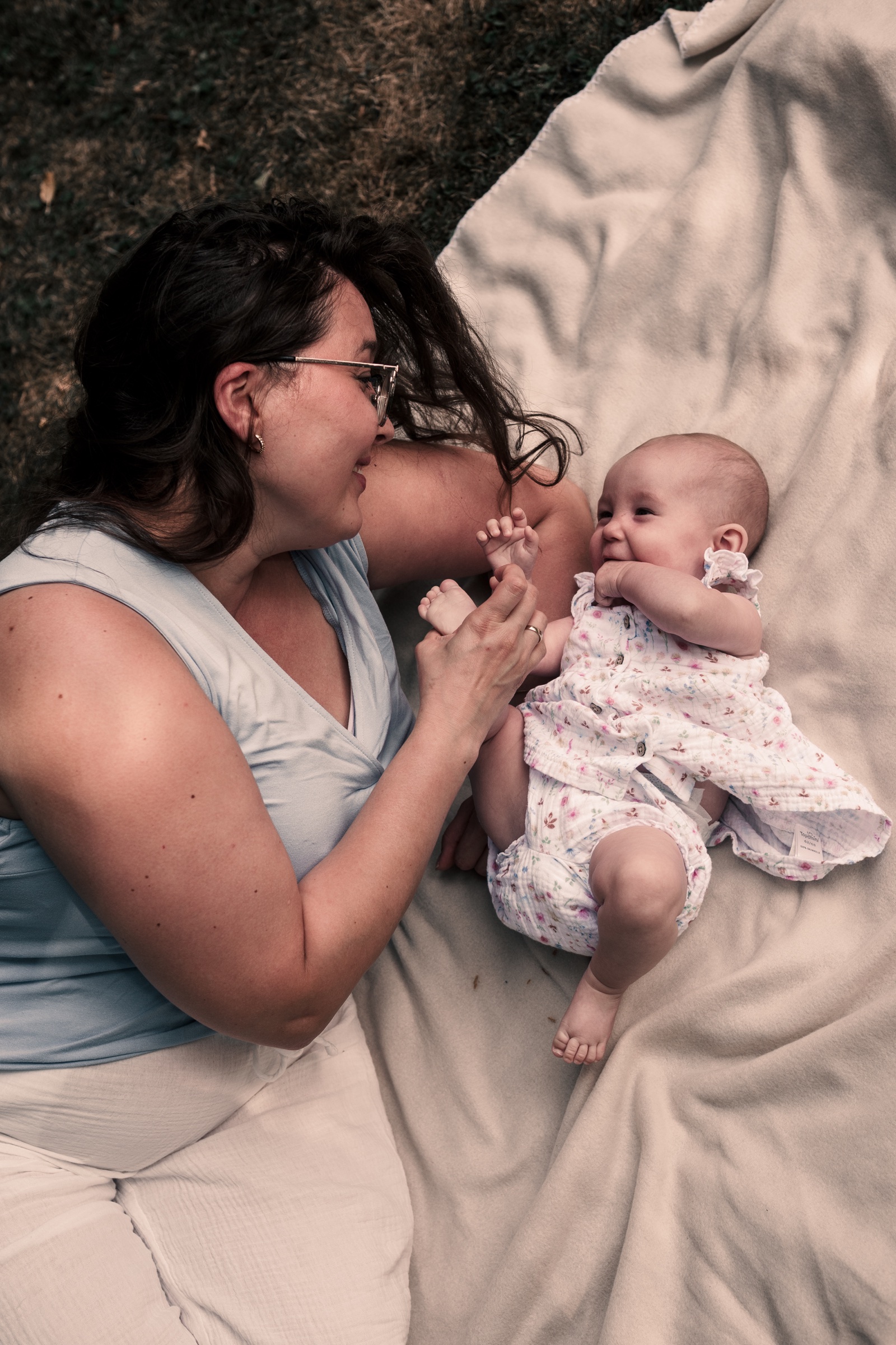 Mutter spielt mit ihrem Baby auf einer hellen Decke