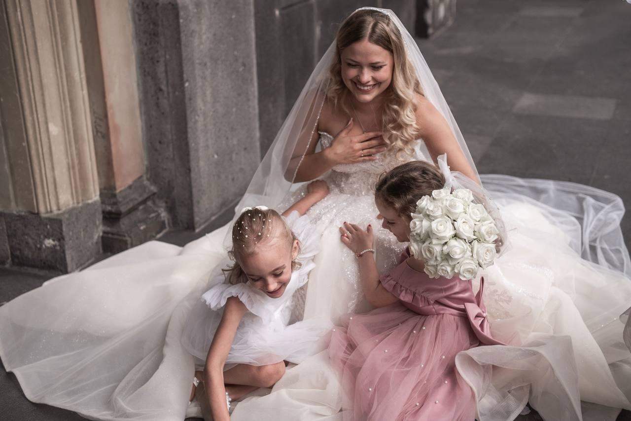 Braut sitzt mit Kindern in einem ruhigen Hochzeitsmoment